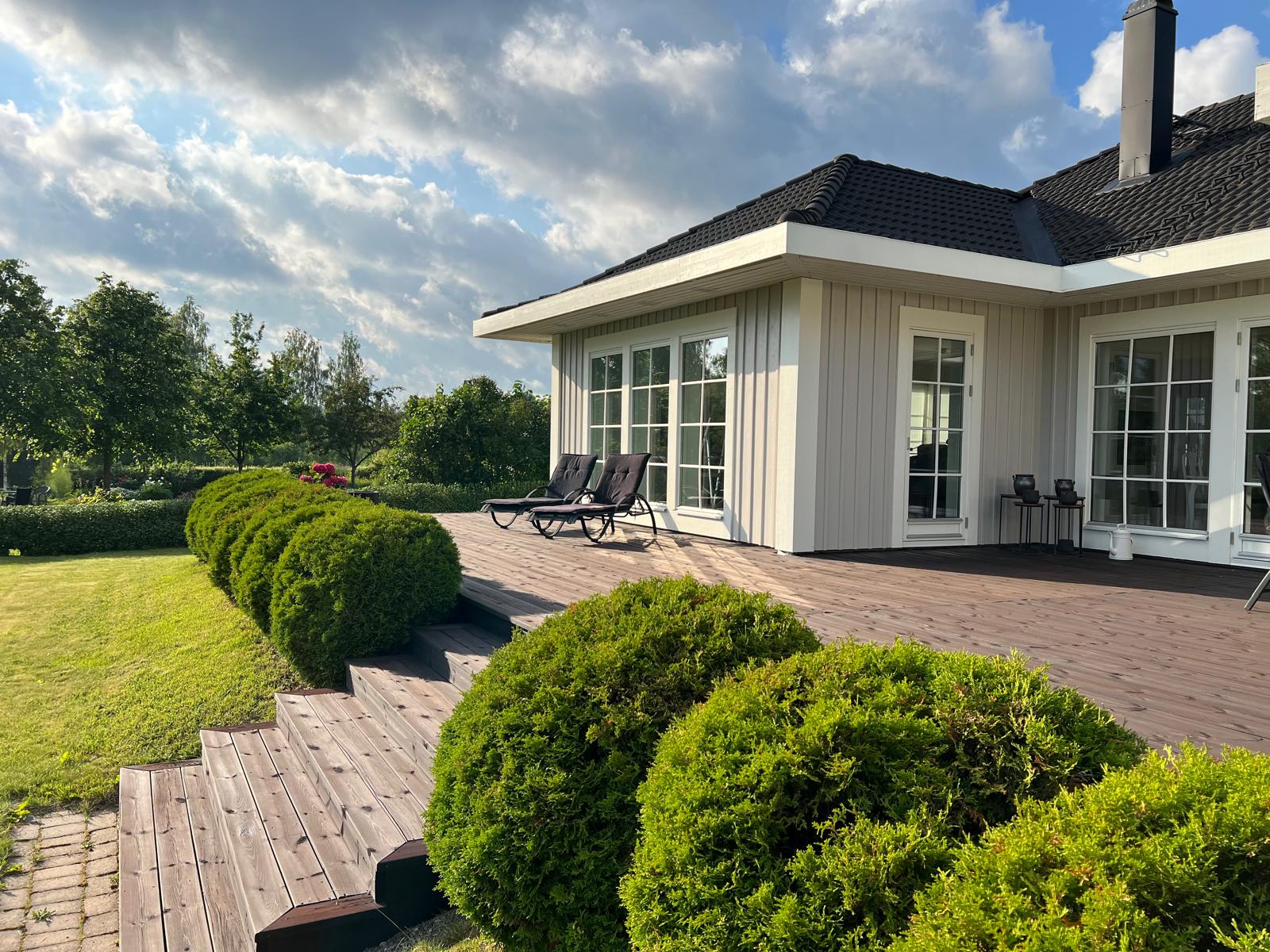 Huset med altan, solstolar och sommarhimmel